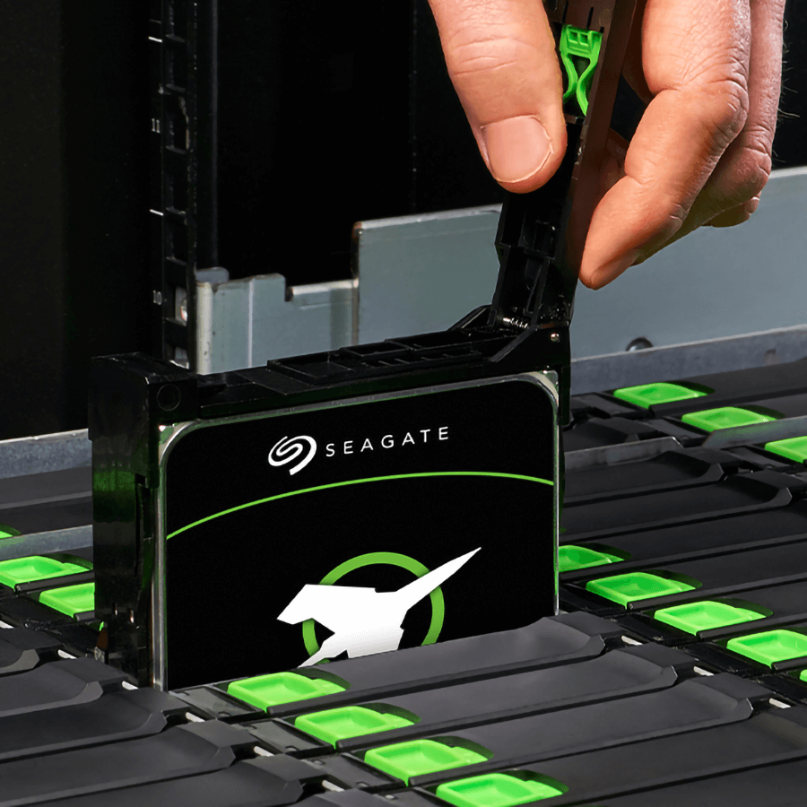 A hand inserts a Seagate hard drive into a server rack. 